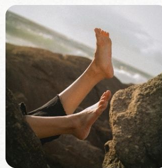 Bare feet resting on rocks by the sea